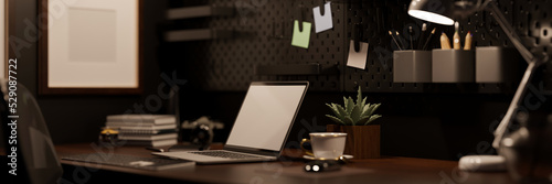 Modern hipster dark office workplace with laptop on wood table over the black wall with black pegboard