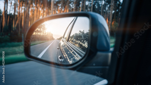 Road trip car mirror. Sun, highway car road reflection in mirror. Summer holidays trip concept.