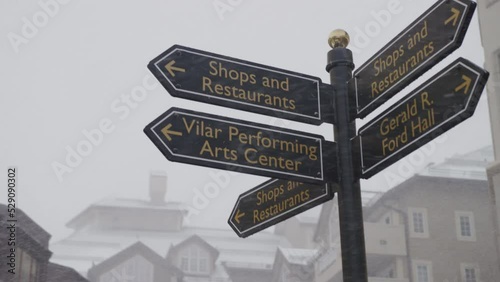 Signs in Beaver Creek Ski Village for shops and restaurants in winter in Colorado in slow motion on snowy day photo