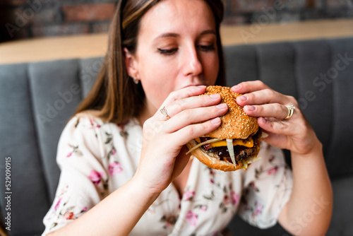 Woman hamburger eat. Hungry Caucasian Female Eating Tasty Burger. Fast food  people and unhealthy eating concept.