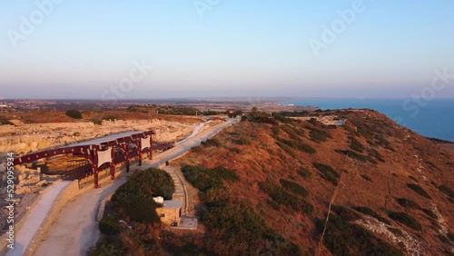 Aerial drone footage of the hill top path to the archaeological site of ancient city of Kourio in district of Limassol, Cyprus. The Greek roman ruins and beach at sunset with no people, from above. photo