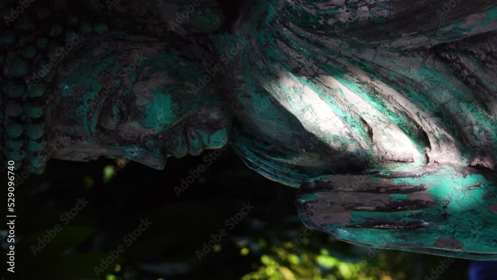Vertical video, rustic copper statue of the Buddha oxidized to green