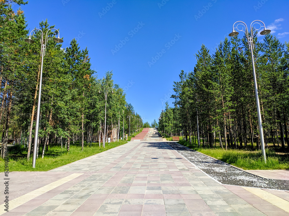 Φωτογραφία Noyabrsk, Russia - July 6, 2022: View of the sidewalk in the city park with wood