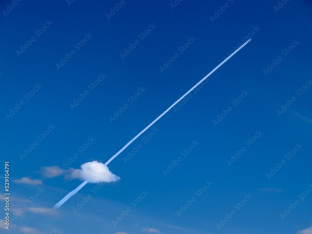 Fototapeta premium Small jets in distance create diagonal chem-trails across blue sky through small puffy lower cloud.