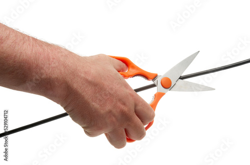 Human hand with scissors cuts a black wire