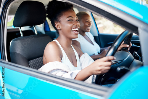 Woman driving, friends and roadtrip for a fun and happy drive while enjoying their vacation, trip and journey together. Black women laughing and talking while sitting in car for an adventure or lift photo