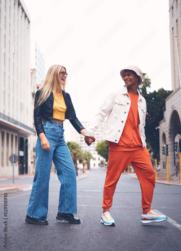 Happy interracial couple with fashion clothing in a urban city street with a smile and love. Trendy, stylish or punk man and woman walking in a town road with funky, edgy and style together