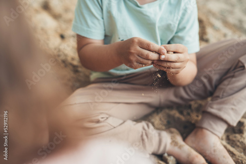 Little boy sitting in the sandbox and playing with sand on playground in summer. Summer vacation fun. Happy family, childhood. Summer outdoor fun activity.