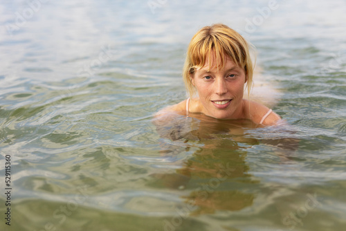 eautiful woman swimming in the ocean. Smiling blonde girl enjoy in sunny day.