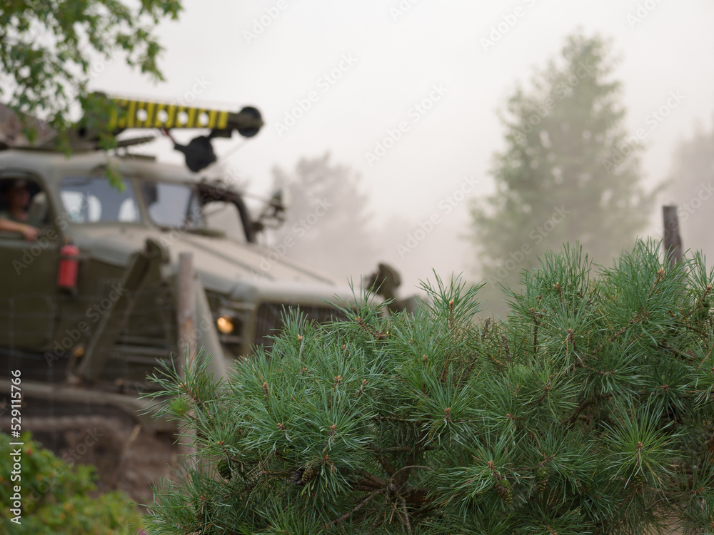 HIGHT SPEED TRACK DOZER ON BACKGROUND OF PINE BRANCHES - Conifer and a military engineering vehicle