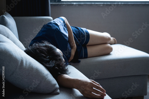 Young man crouching in the sofa, suffering from stomachache.
