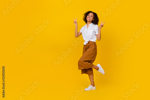 Full length photo of excited charming person hands fingers show v-sign empty space isolated on yellow color background