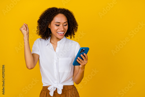 Print op canvas Photo of delighted excited girl raise fist luck achievement hold telephone isola