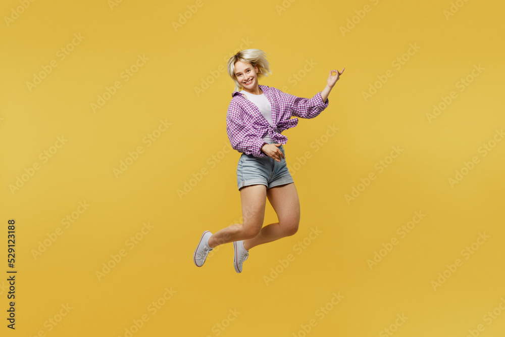 Full body young musician happy blonde woman 20s wear pink tied shirt white t-shirt jup high play guitar do hand gesture isolated on plain yellow background studio portrait People lifestyle concept. Full body young musician happy blonde woman 20s wear pink tied shirt white t-shirt jup high play guitar do hand gesture isolated on plain yellow background studio portrait People lifestyle concept.