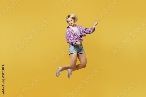 Full body young musician happy blonde woman 20s wear pink tied shirt white t-shirt jup high play guitar do hand gesture isolated on plain yellow background studio portrait People lifestyle concept.