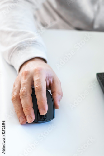 Closeup of male hand working with wireless computer mouse on white work desk