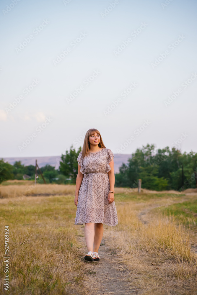 A young woman walks in a clearing. A walk in the park or forest. Outdoor recreation. The atmosphere of freedom and nature. A young woman walks in a clearing. A walk in the park or forest. Outdoor recreation. The atmosphere of freedom and nature.