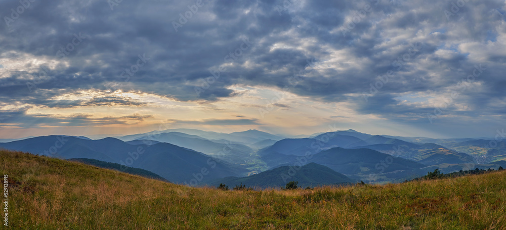 Summer evening at the top of the mountain. Panorama of the valley with roads and villages. Countryside in the Ukrainian Carpathians