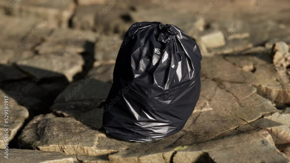 black trash bag lay on a rocky beach black trash bag lay on a rocky beach