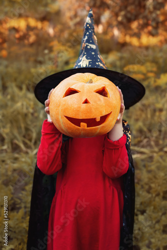 Child in halloween costume with pumpkin. Halloween celebration.