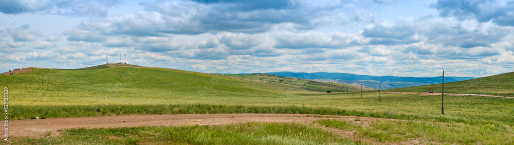 Bald Mountain in the Buryat Republic of Russia. Green hills against a blue sky with clouds. Bald Mountain in the Buryat Republic of Russia. Green hills against a blue sky with clouds.