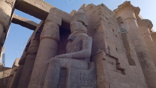 Hand-held Shot Of A Pharaoh Statue Sitting Down Surrounded In The Luxor Temple, Egypt photo