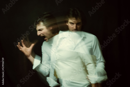 schizophrenic portrait of psychopathic man with mental disorders in white shirt on dark background photo