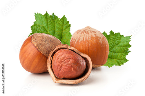 hazelnuts with green leaves on white background.