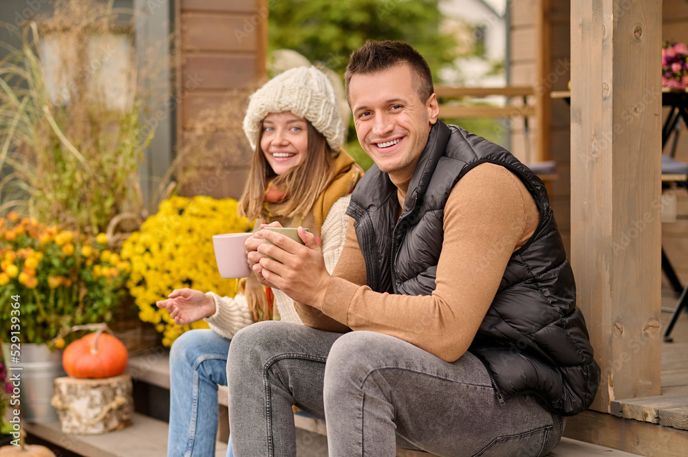 Fototapeta premium Cheerful young couple seated on the veranda