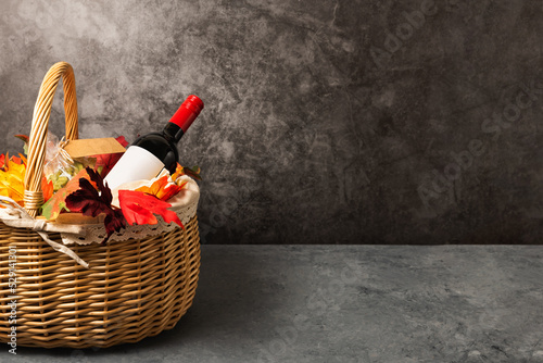 Bottle of red wine with apples and cookies in a gift basket. Hamper for autumn Thanksgiving festival