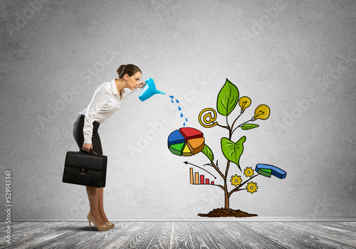 Young businesswoman in empty room watering drawn growth concept with can