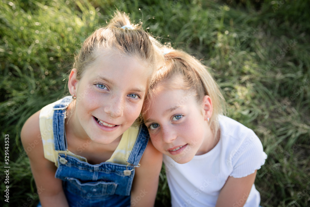 two pretty young girls sisters friends have fun outside in a meadow in summer and are happy two pretty young girls sisters friends have fun outside in a meadow in summer and are happy