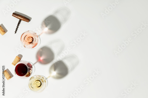 Flat-lay of red, rose and white wine in glasses on white background, copy space photo