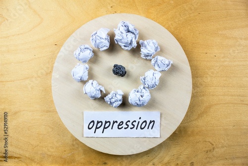 The word OPPRESSION on a piece of paper on a wooden table. The concept of oppression, bullying, ridicule, reproaches and swearing at work or in everyday life.