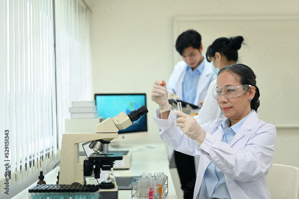 Senior female research scientist is conducting experiment in laboratory. Medicine, microbiology development concept Senior female research scientist is conducting experiment in laboratory. Medicine, microbiology development concept