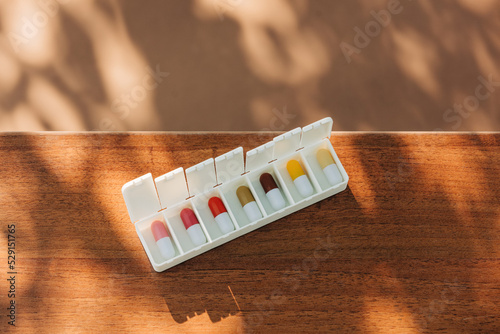 Colored pills in sorter on table photo