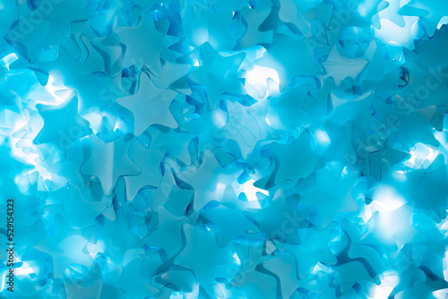 Bright colorful blue stars. Pattern from sequins, tinsel, confetti for new year, holiday, birthday. Festive background for party, carnival, celebrate. Decor, surprise, gift. Close up. Top view.