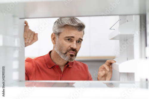 Canvas-taulu Upset middle aged man looking inside empty fridge
