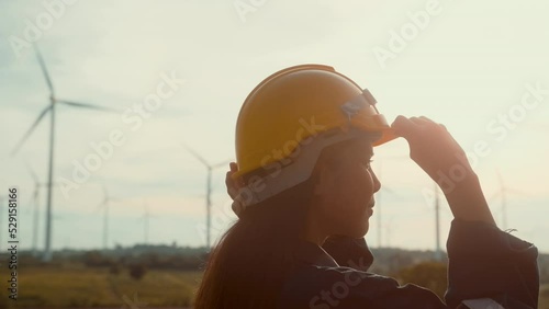 a woman engineer is putting a protective helmet on her head at sunset.