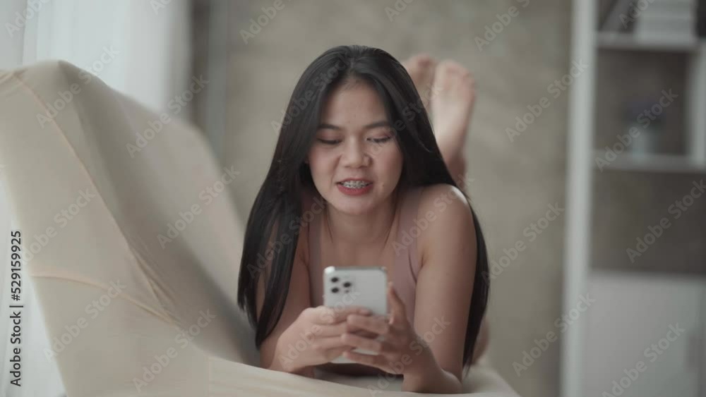 Beautiful young woman in panties making selfie by smart phone while lying on couch at home.