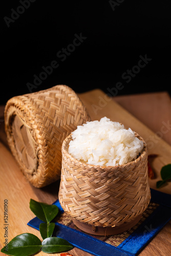Asian Food concept Glutinous rice or Sticky rice in bamboo wicker on wooden board and black background with copy space