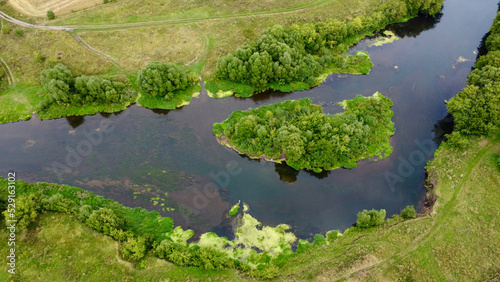 Aerial photography. View of a small island covered with green bushes in the middle of the river.