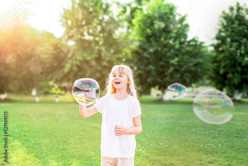 A child girl blows soap bubbles. There is a big soap bubble.