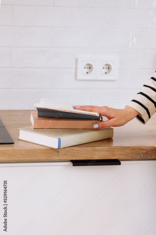 Female holding her hand on pile of books on wooden table background. Education, self-learning, book swap, hobby, relax time. The concept of a student overloaded with learning. Female holding her hand on pile of books on wooden table background. Education, self-learning, book swap, hobby, relax time. The concept of a student overloaded with learning.