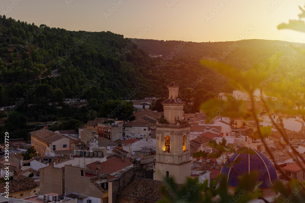 Old Spanish city located between mountains and framed with the leaves of a plant with the sunset light