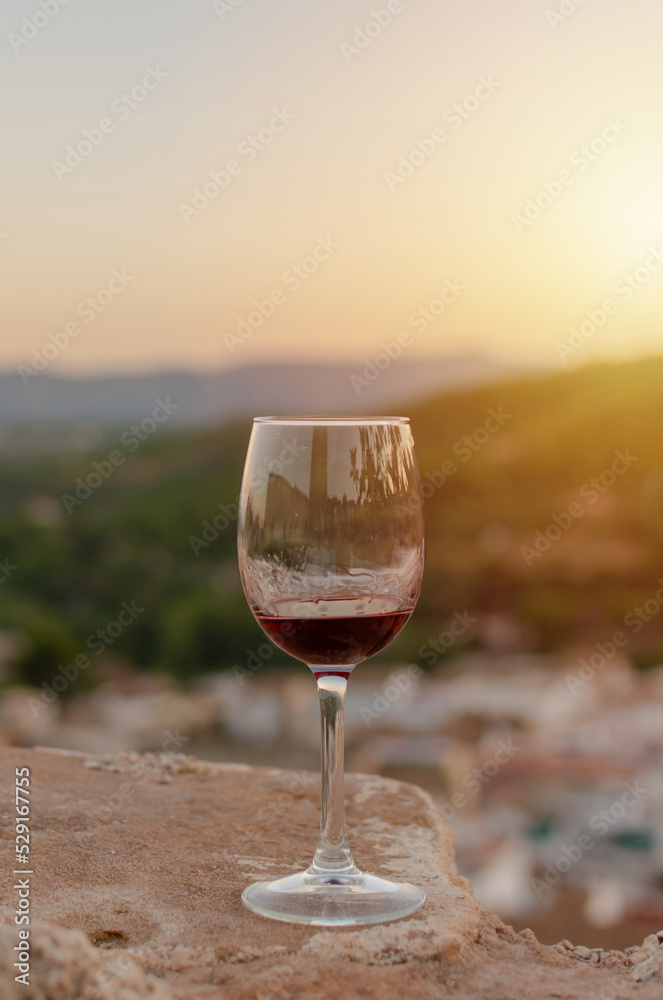 Close-up of a glass of red wine with a background of mountains with sunset light