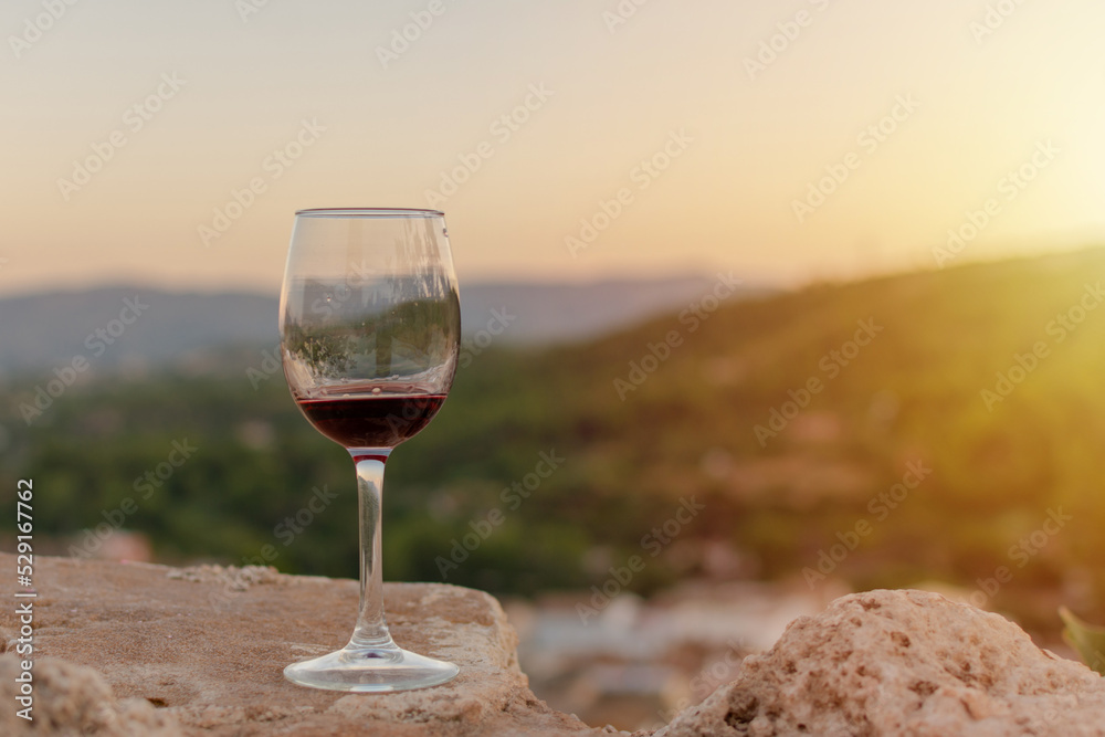Glass of red wine with background of mountains and sunset light