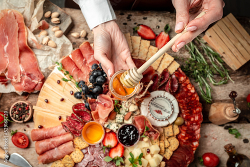 Traditional italian antipasto. Assorted cheeses, grapes, olives, prosciutto, rosemary. Delicious appetiser Italian prosciutto and Spanish Iberian ham snack