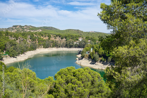 Spectacular panoramic views of the Guadalhorce reservoir  next to the Caminito del Rey in Malaga  Spain. Turquoise blue water and forest with blue sky on a sunny day.