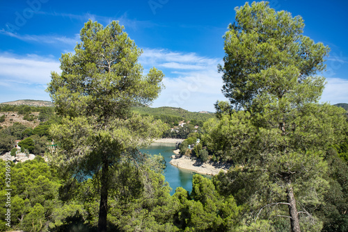 Spectacular panoramic views of the Guadalhorce reservoir, next to the Caminito del Rey in Malaga, Spain. Turquoise blue water and forest with blue sky on a sunny day.